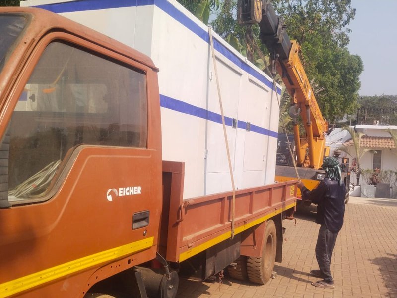 Crane loading a soundproof generator onto a delivery truck in Goa